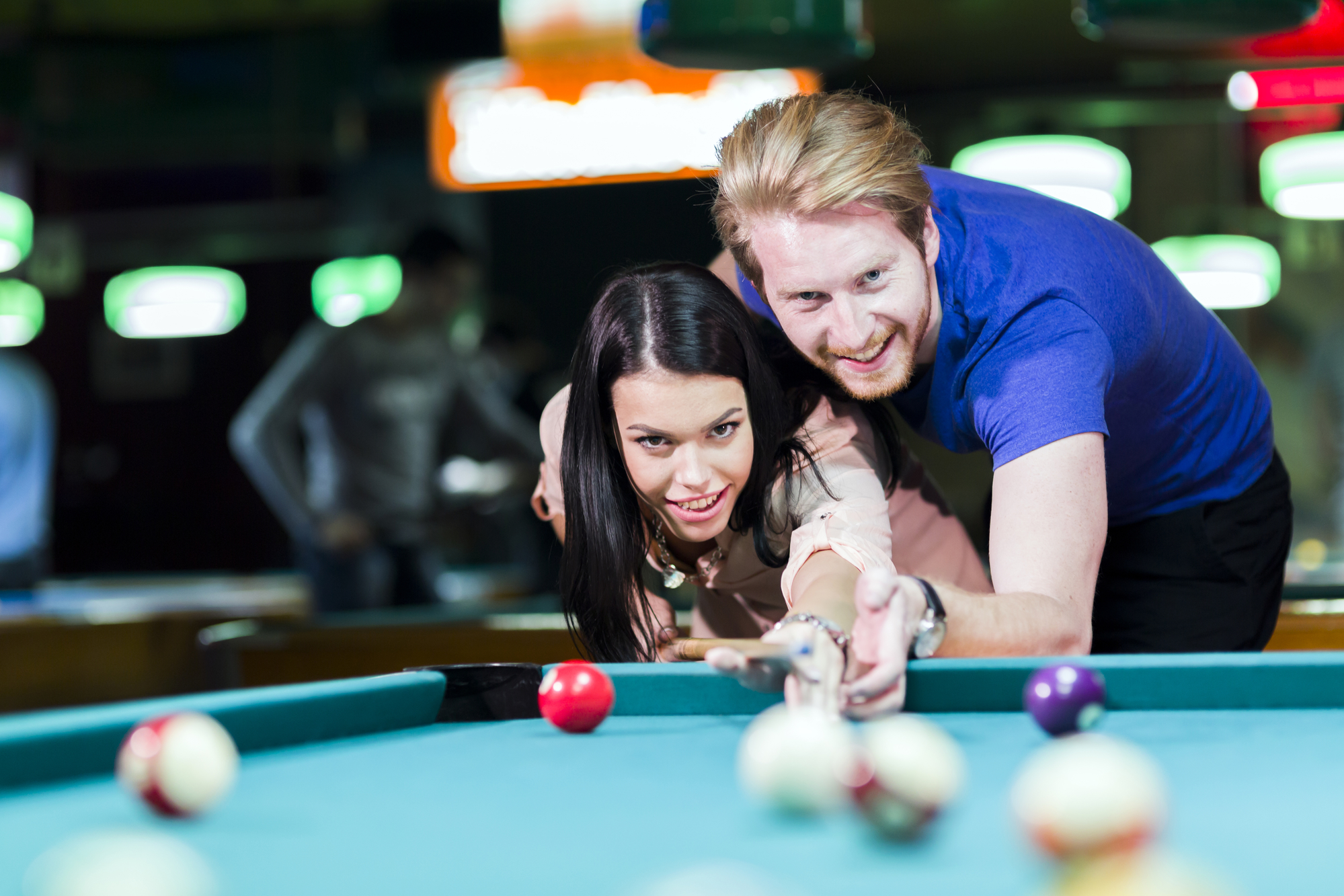 Young handsome man and woman flirting while playing billiards